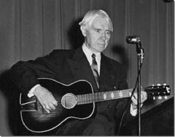 Carl Sandburg with guitar at mic